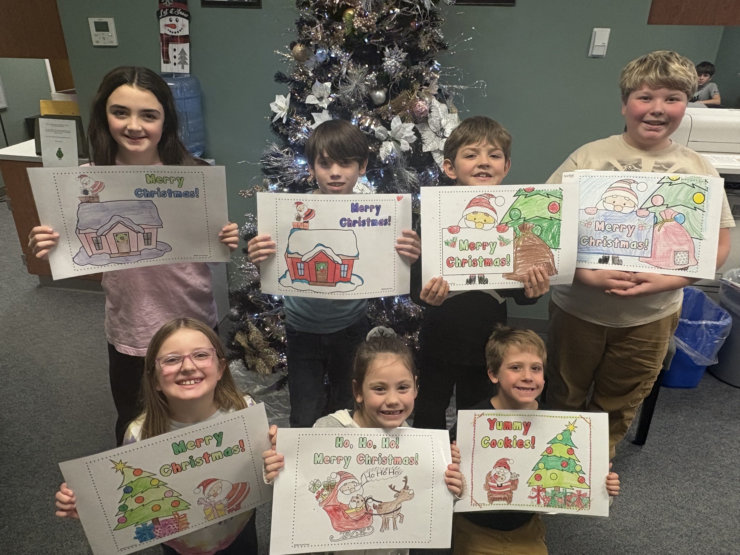 Group of elementary students holding holiday artwork
