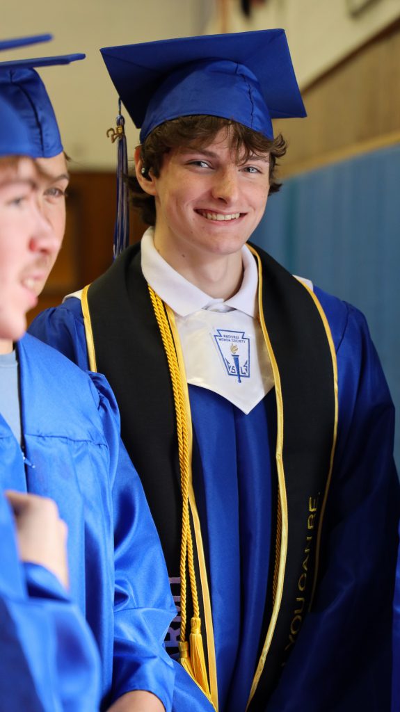 student wearing graduation cap and gown smiling
