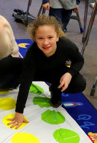 An elementary student looks up from a game of Twister.