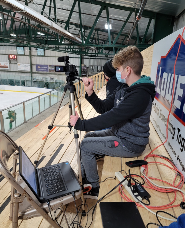 A high school student films a hockey game in the dome.