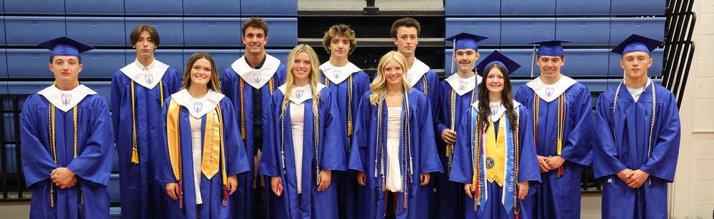 Several graduates pose together in a gym.