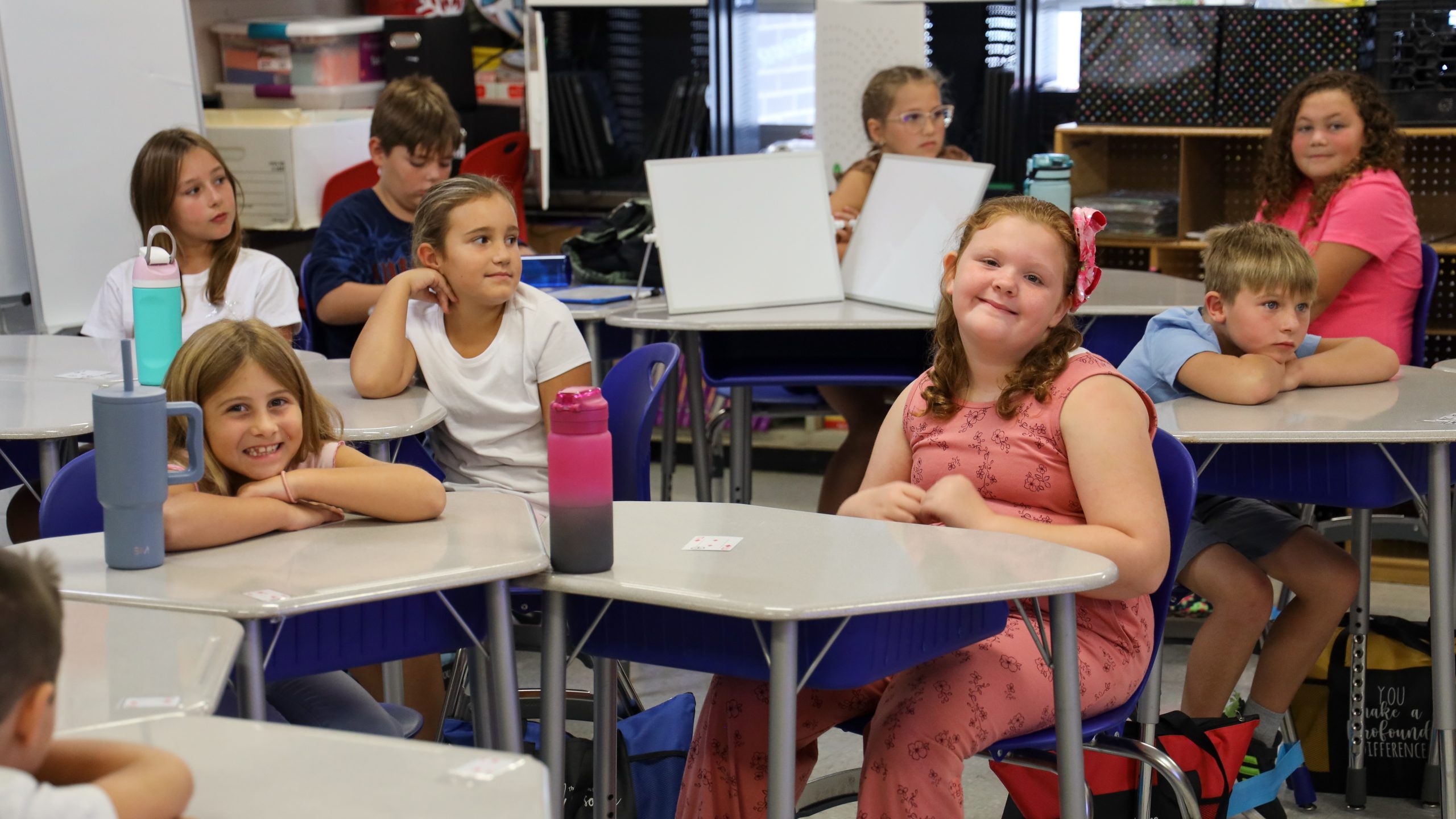 Students smile in a classroom setting.