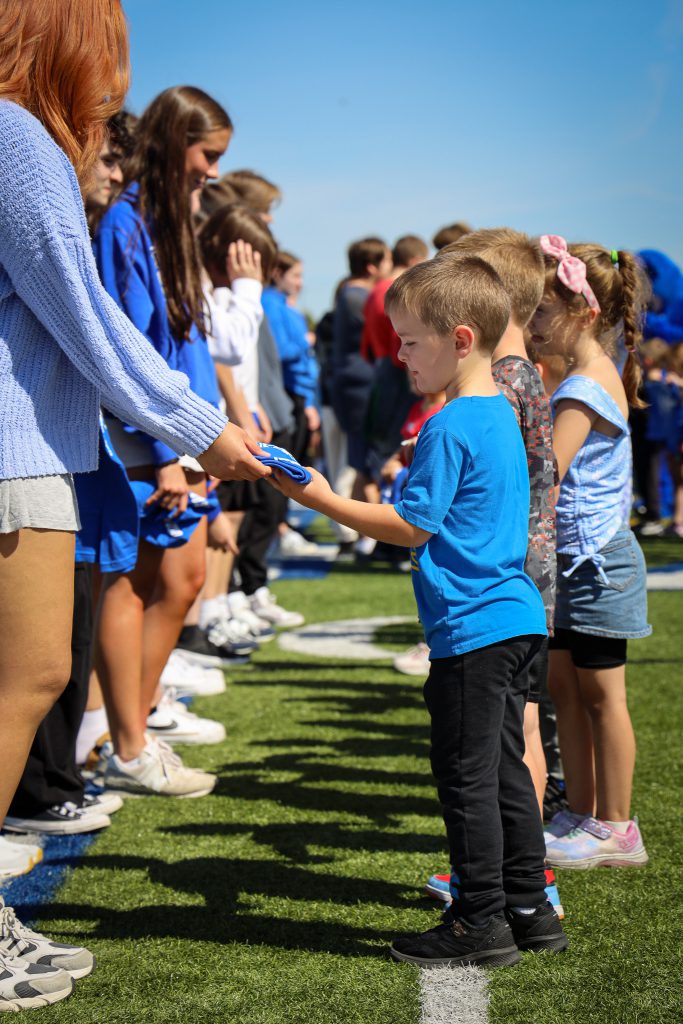 A young student standing in a line accepts a t-shirt from a senior.