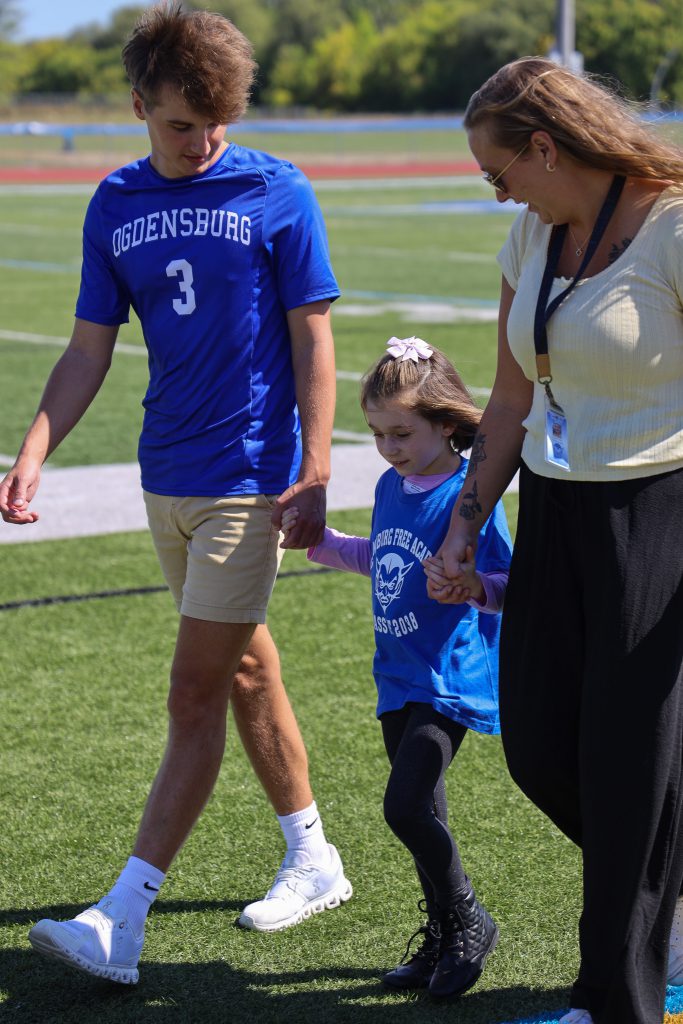 A Madill student holds hands with a senior and a teacher.
