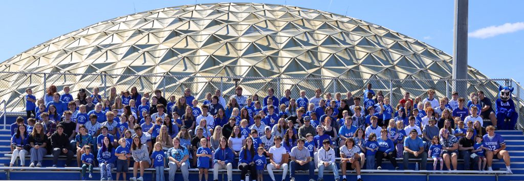 All seniors and kindergarteners sit on bleachers in front of the OFA dome.