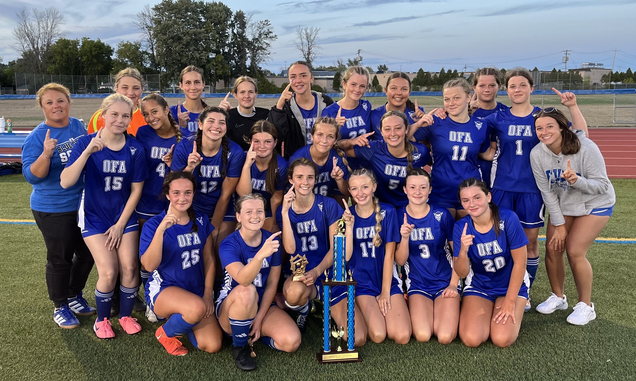 The girls varsity soccer team poses together with a trophy.