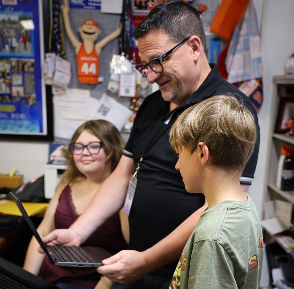 A teacher showing a laptop to a student.