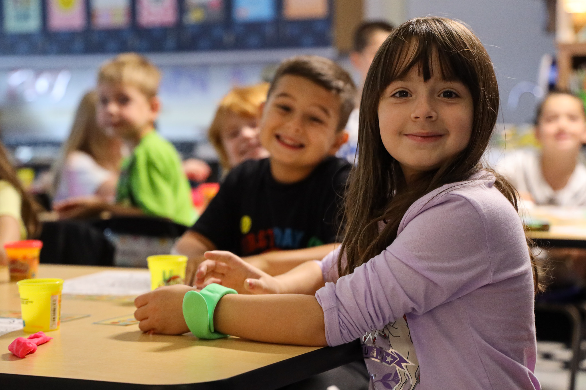 A young student sits proudly in her classroom seat.