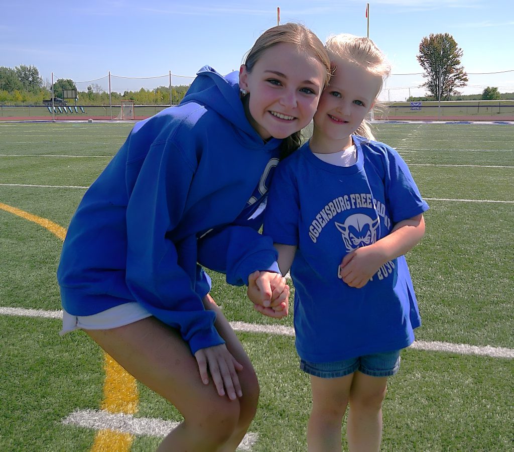 An OFA senior crouches next to a young student.