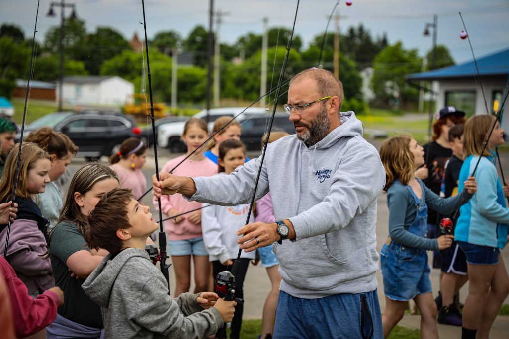 Students and adult holding fishing poles