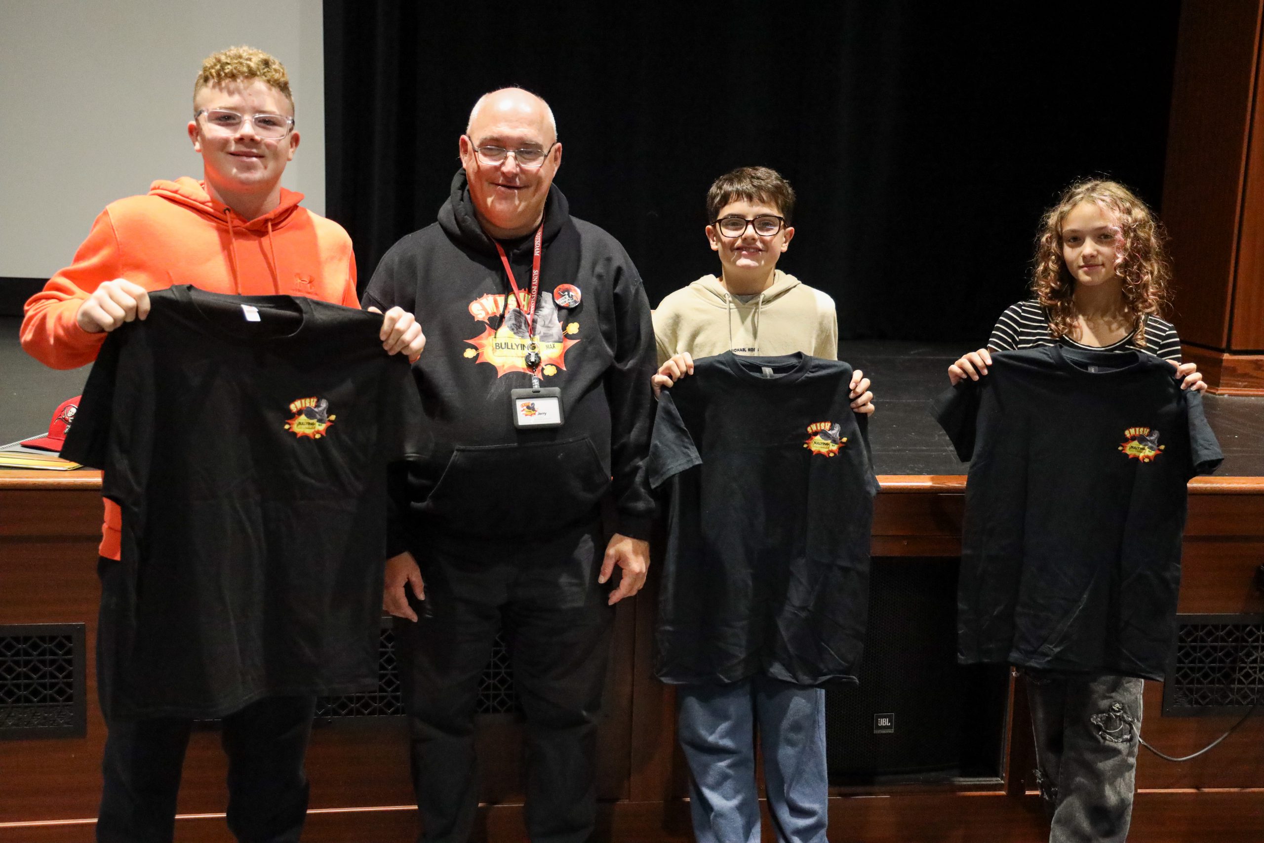 Students holding t-shirts with a guest speaker