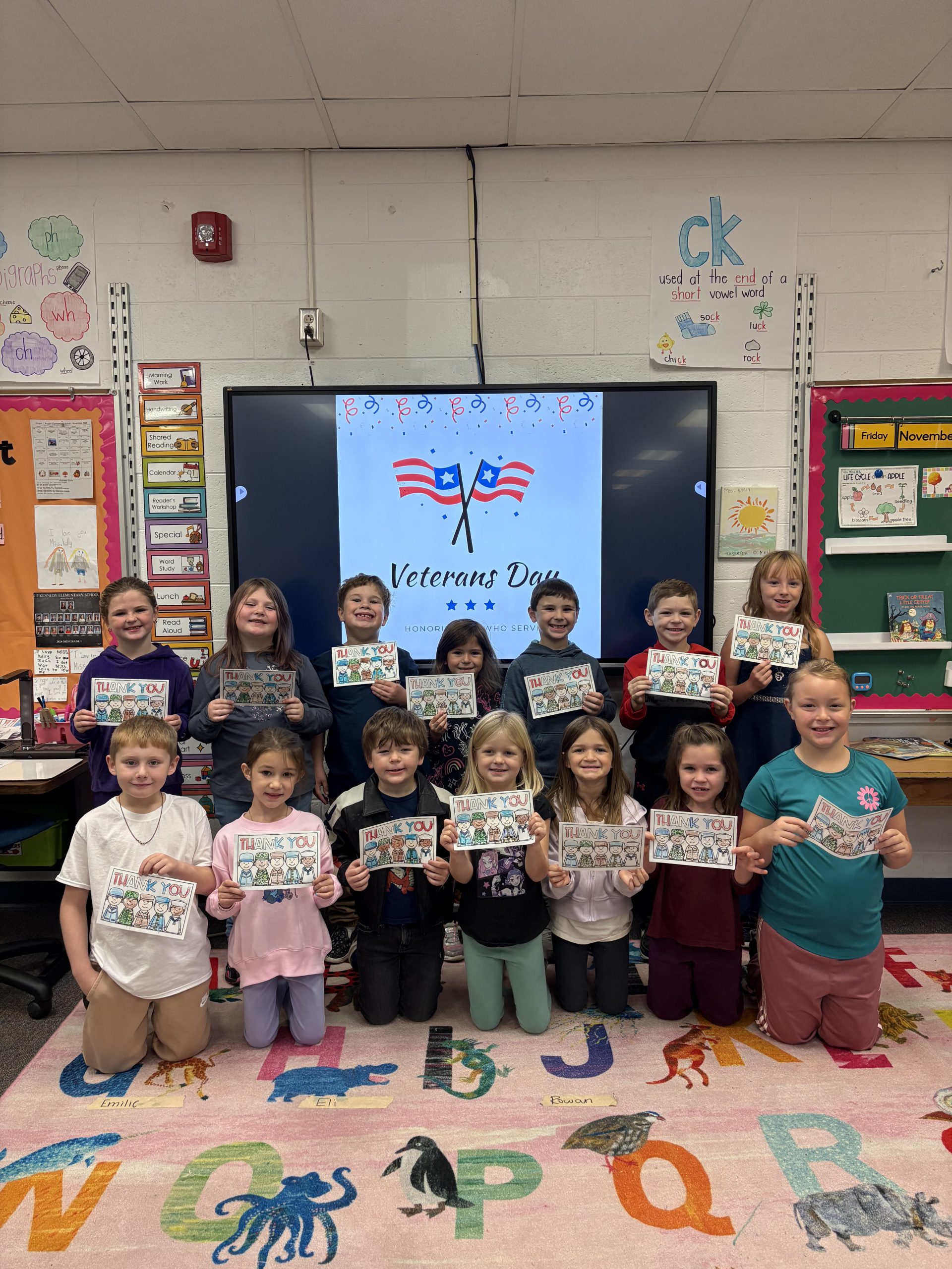 Group of elementary students holding Veterans Day cards they created