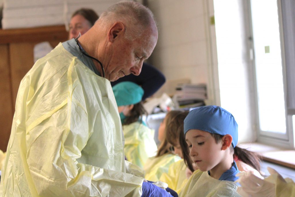 Male hospital staff member helping male student put on hospital scrubs