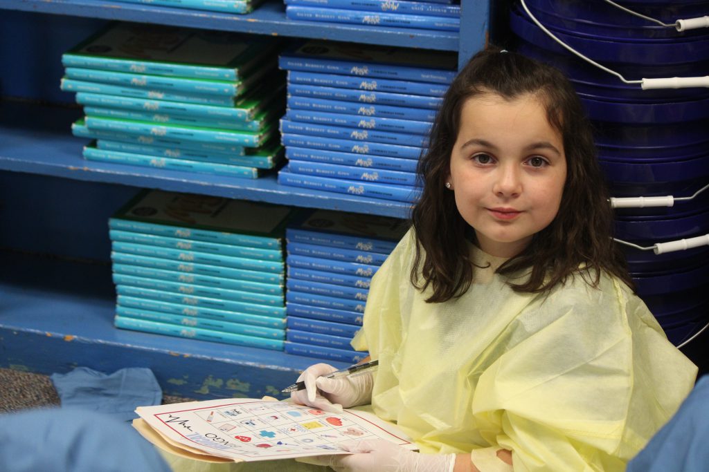 Female elementary student working on a classroom activity wearing hospital scrubs