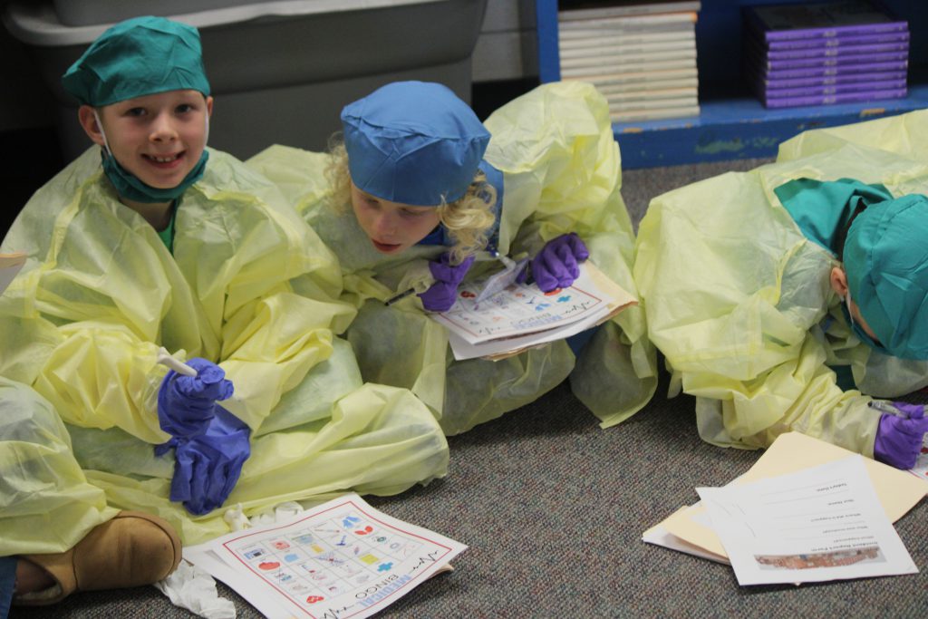 Group of elementary students participating in a classroom activity wearing hospital scrubs