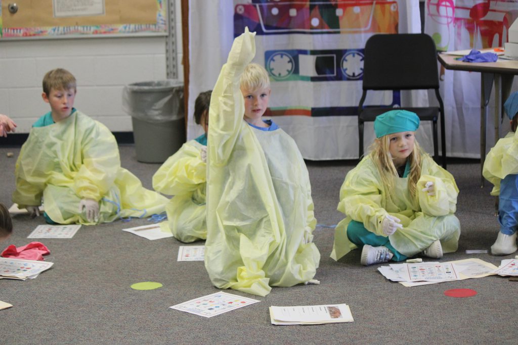 Group of elementary students in the classroom wearing hospital scrubs