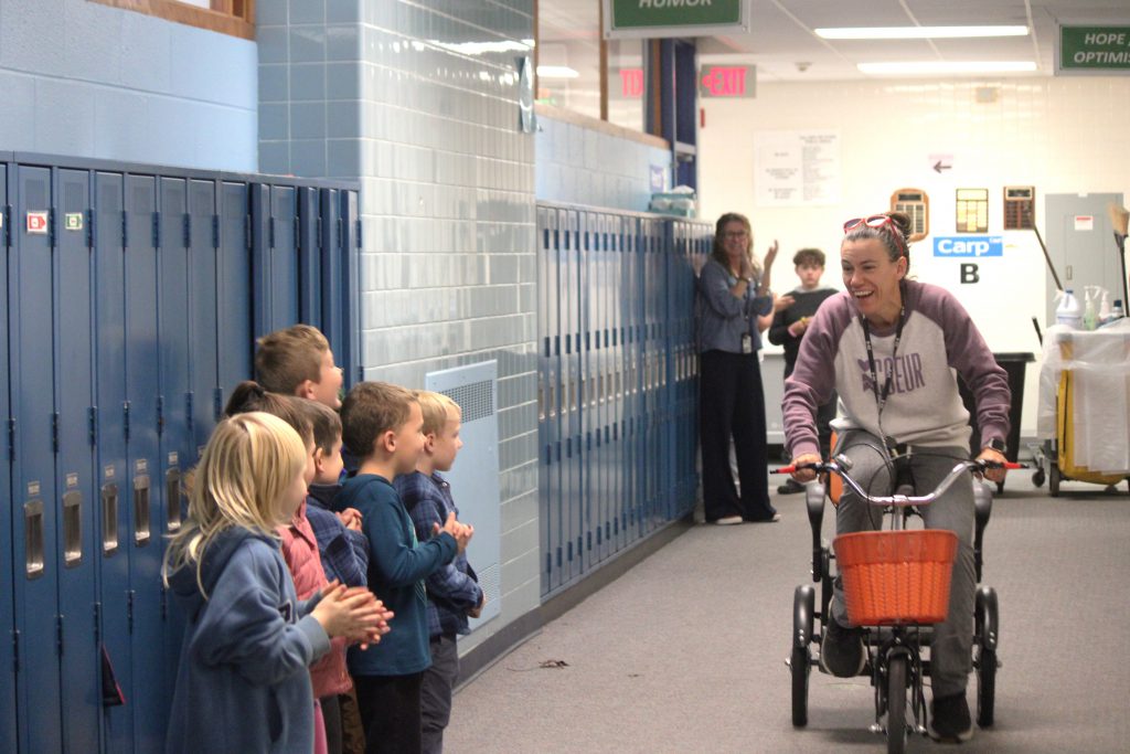 Amy Farrell riding the tricycle through the hallways