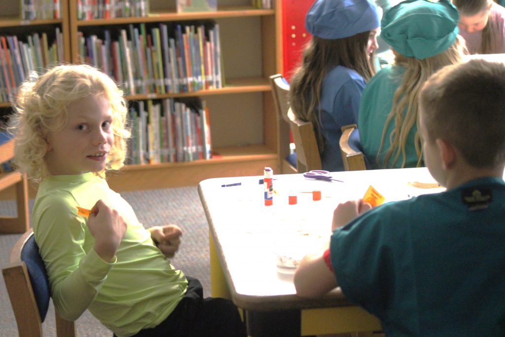 Male elementary student sitting at a table working on a project