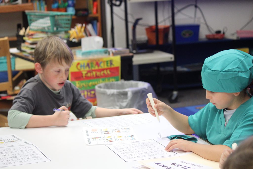 Elementary students sitting at a table working on a project