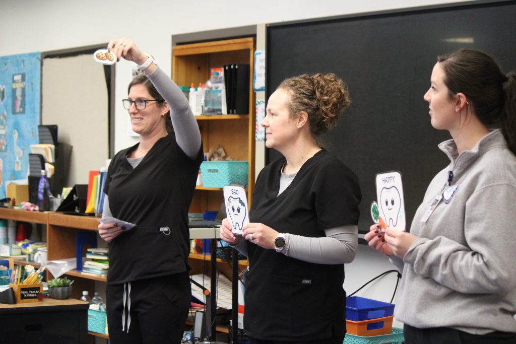 Female medical experts in front of elementary students