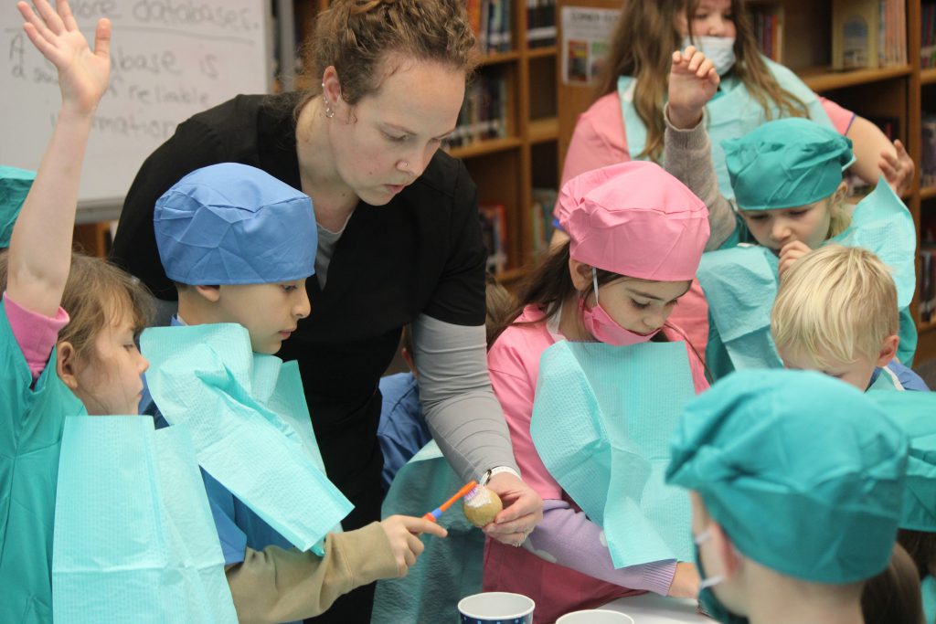 Group of elementary students gathered around female dental staff member