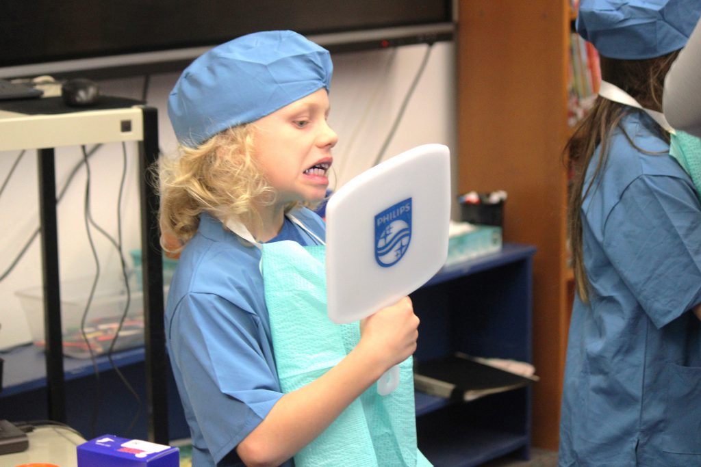 Male elementary student looks at his teeth in the mirror
