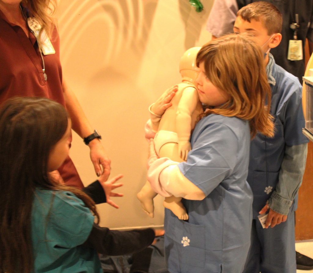 Female elementary student holding baby doll