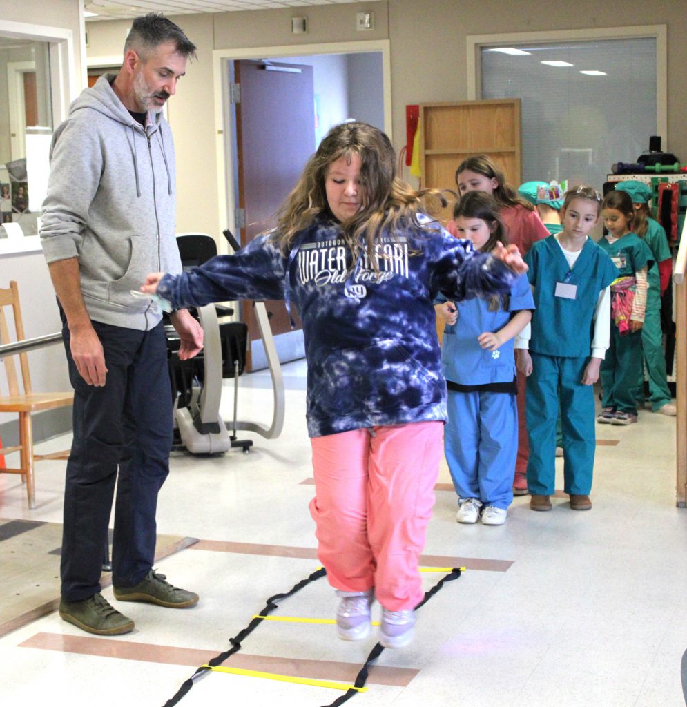 Female elementary student participating in activity while male hospital staff member supervises