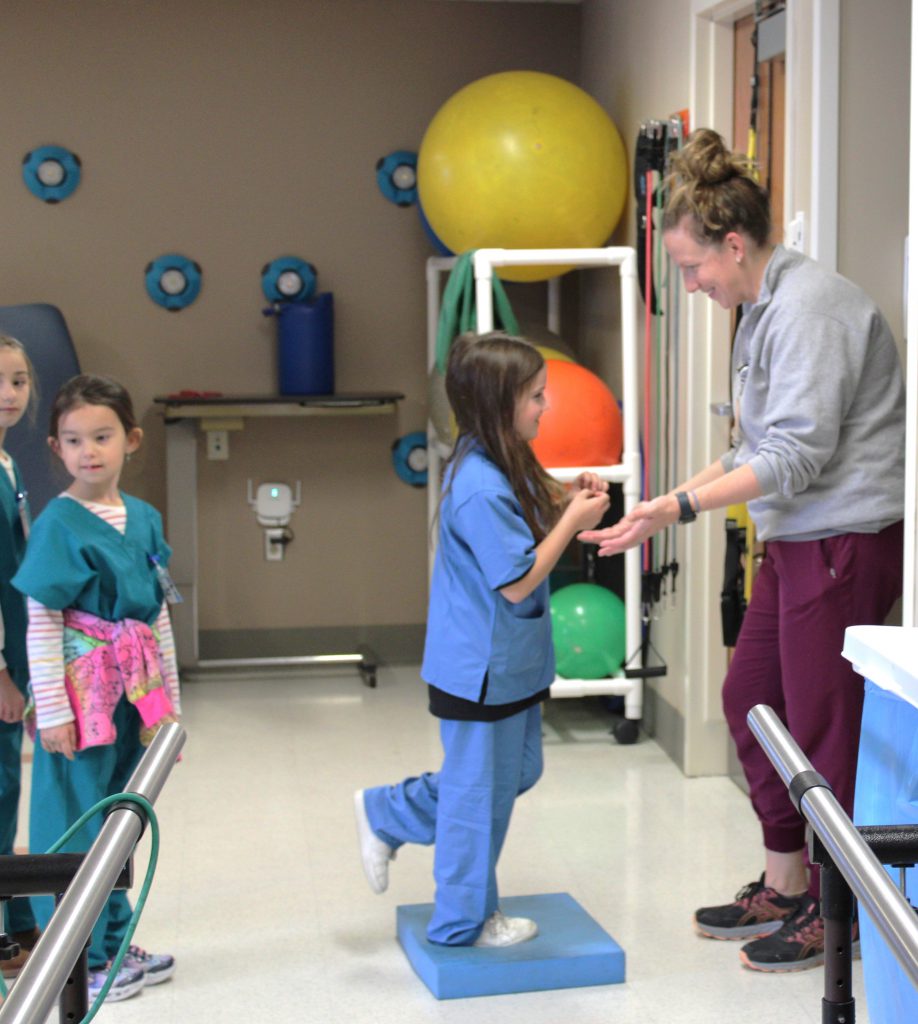 Female elementary student balancing with hospital staff member