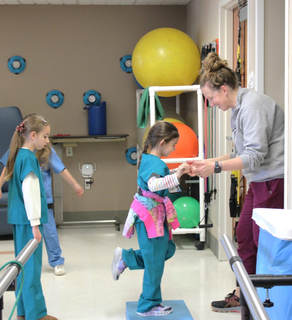 Female elementary student balancing with hospital staff member