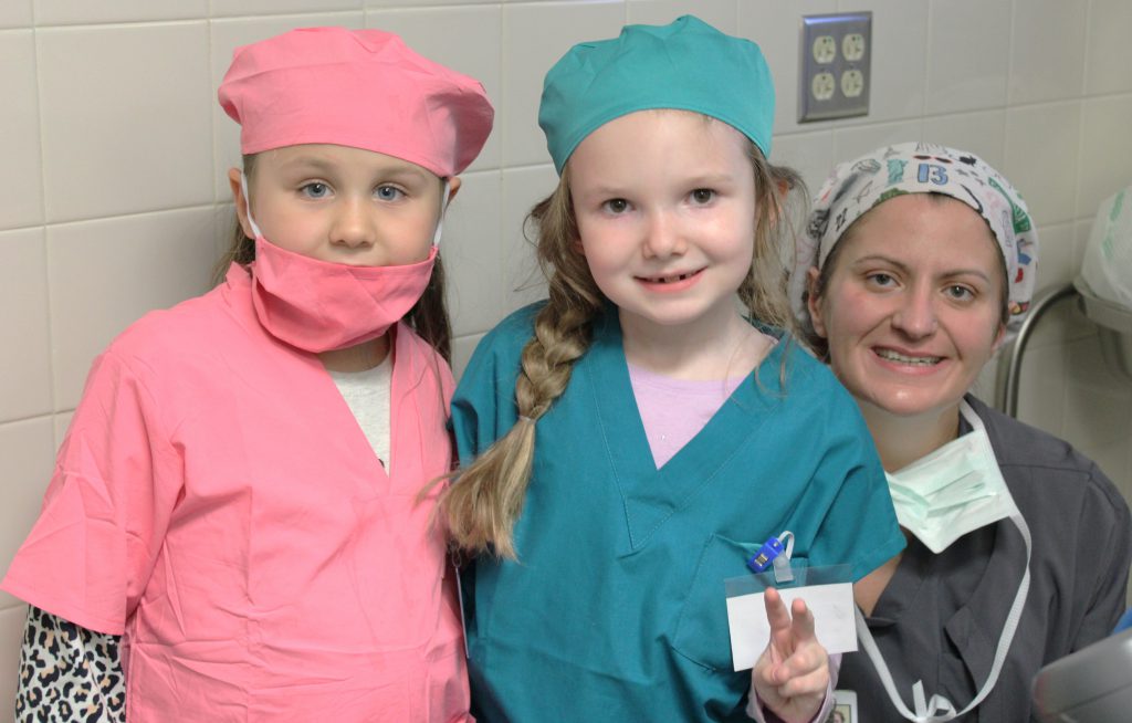 Two female elementary students with a female hospital staff member