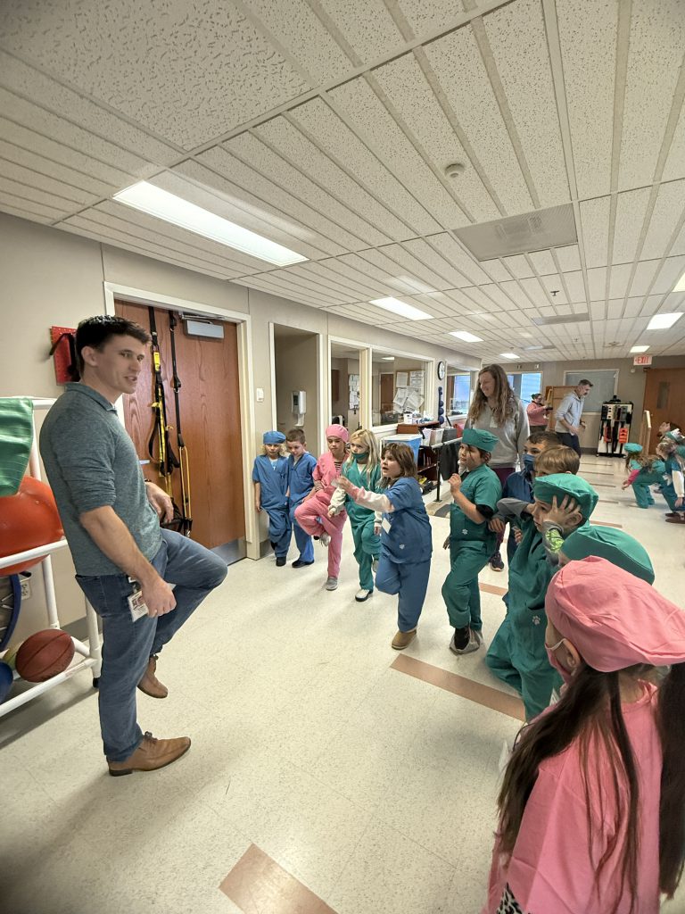 Elementary students participate in stretching with hospital staff member