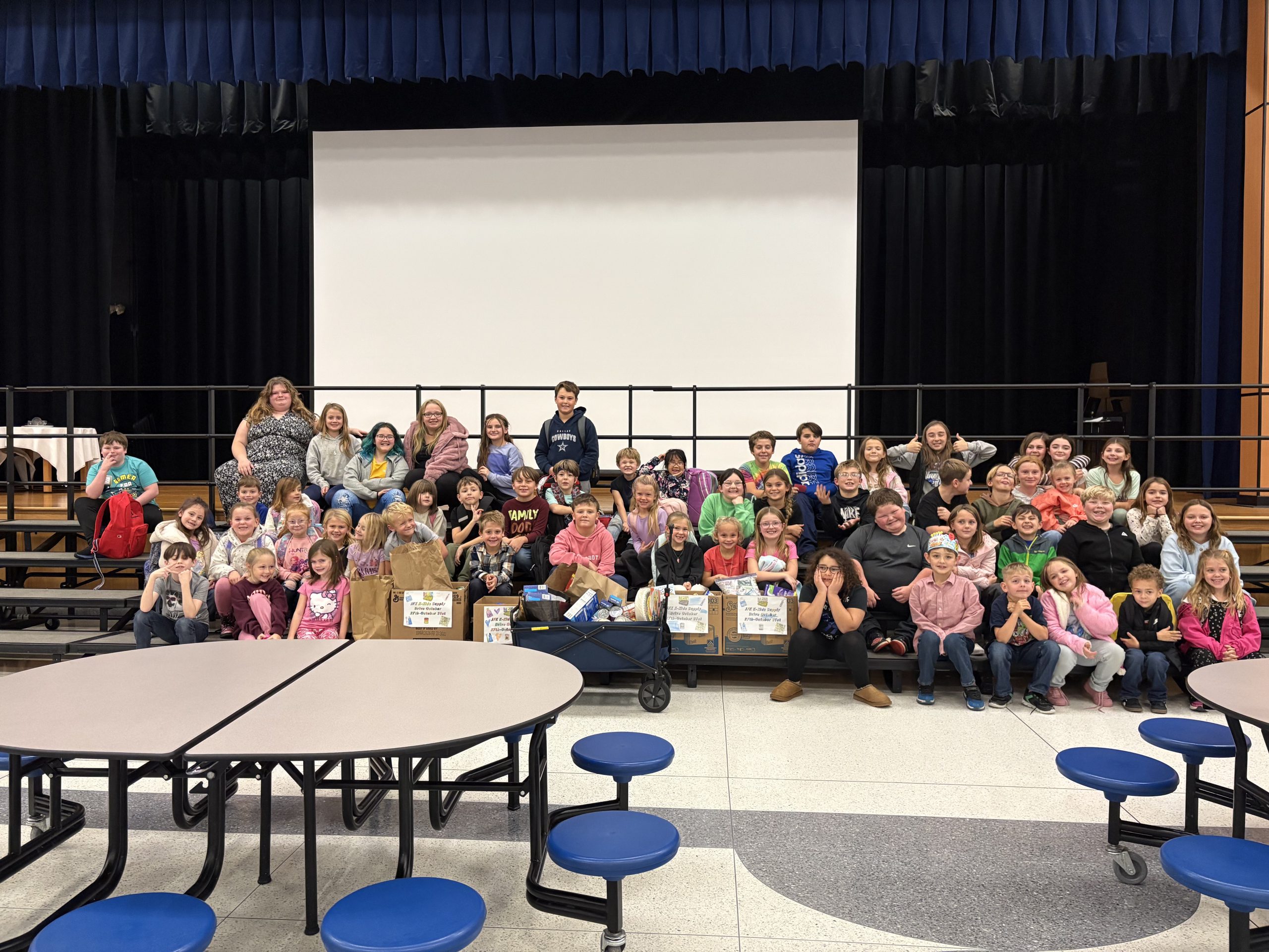 Group of elementary students holding brown paper bags with food donations