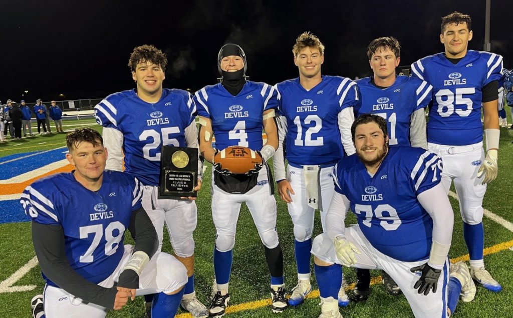 Group of high school football players holding a football and an award
