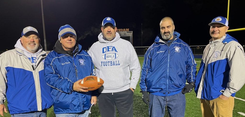 High school football coaches holding a football