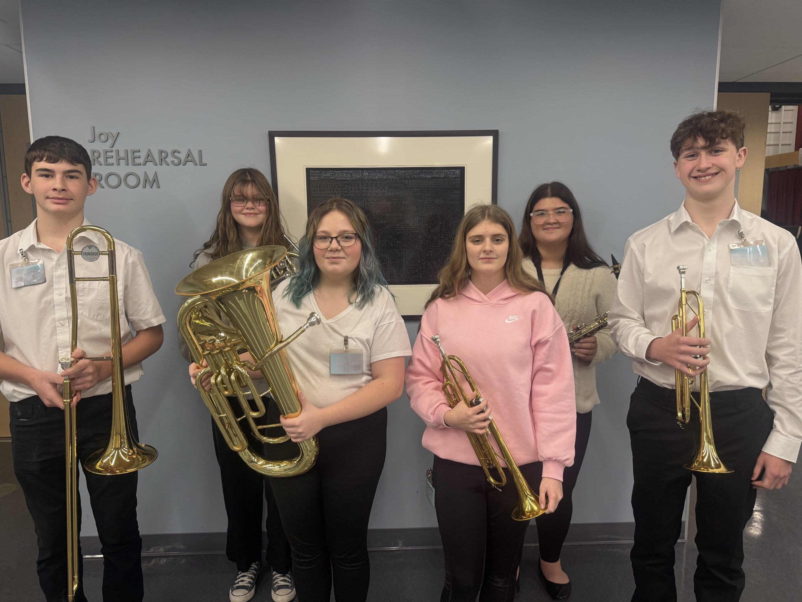 Small group of teenage students smiling and holding instruments