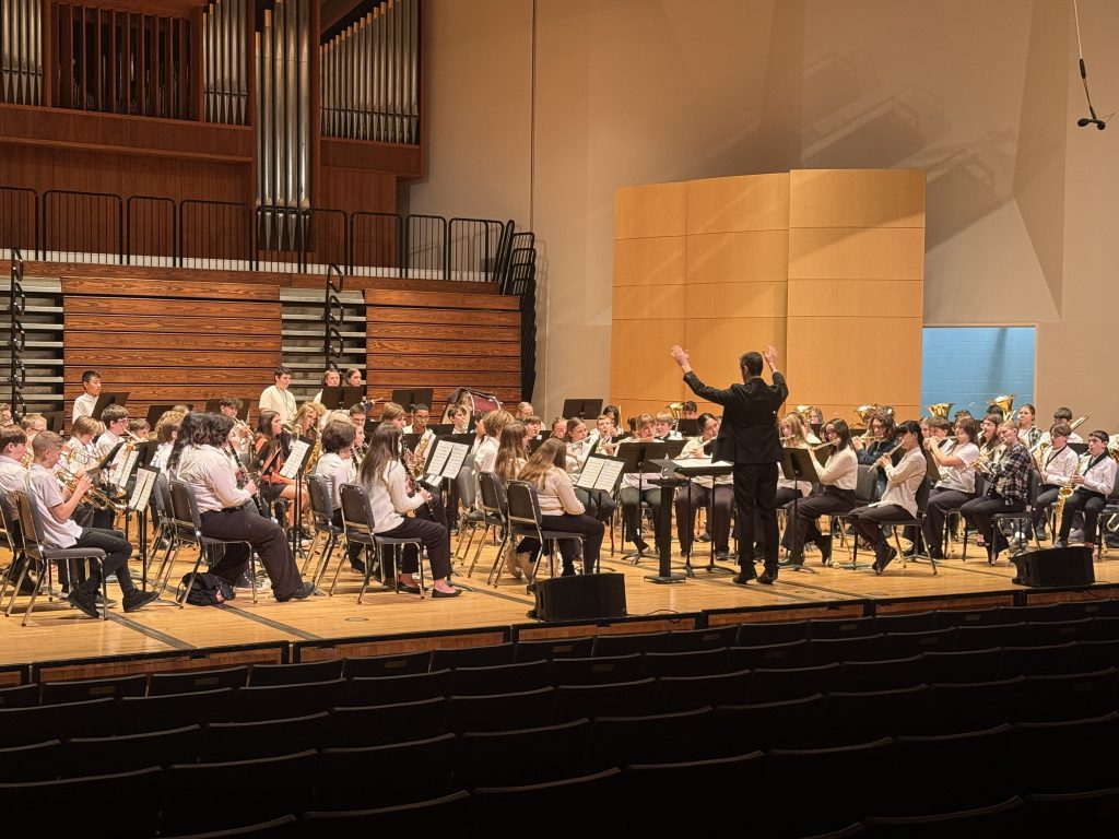 Large group of teenage students playing instruments on stage
