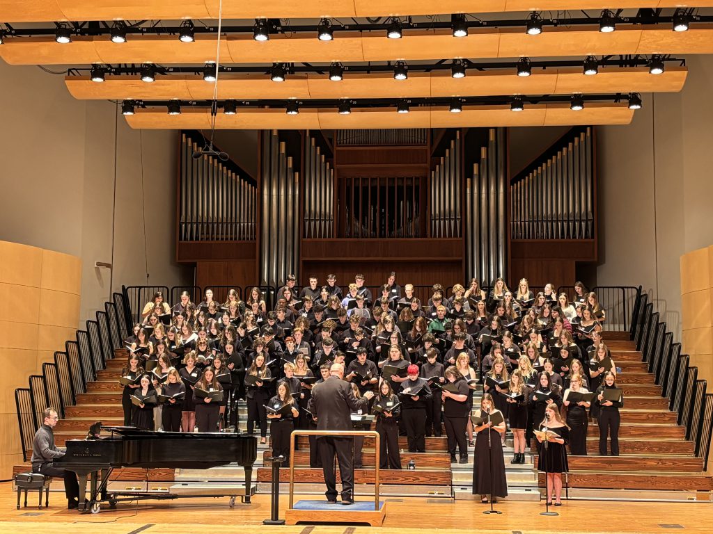 Large group of teenage students singing on stage