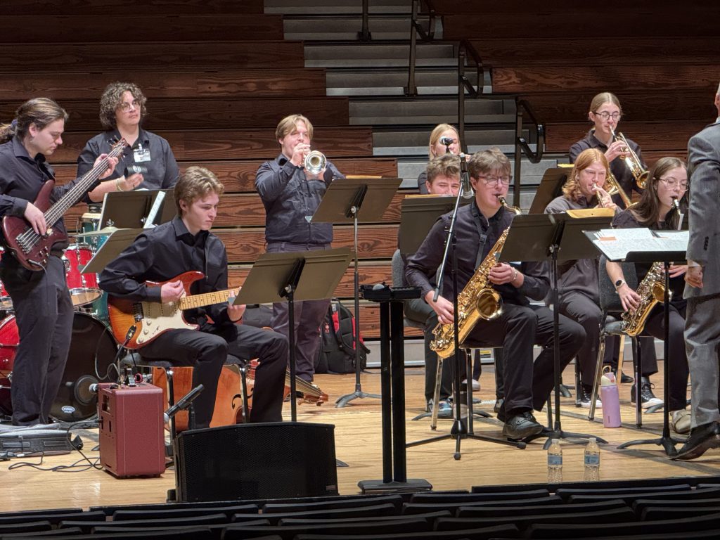 Large group of teenage students playing instruments on stage