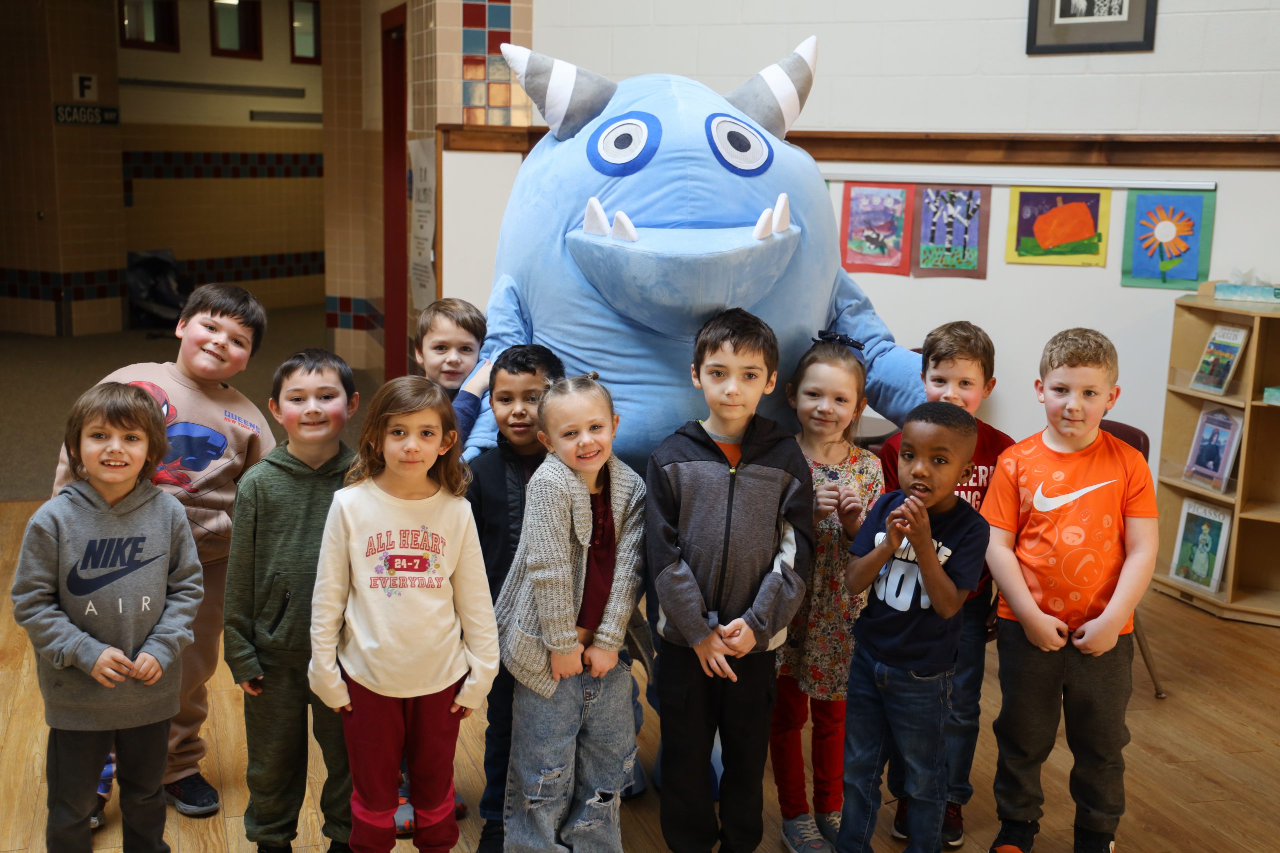 Small group of elementary students with a blue monster mascot