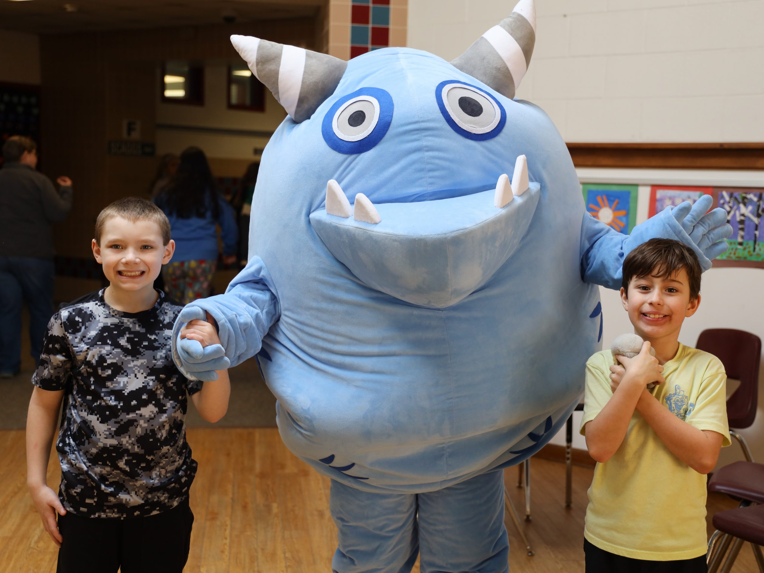 Two male elementary students with a blue monster mascot