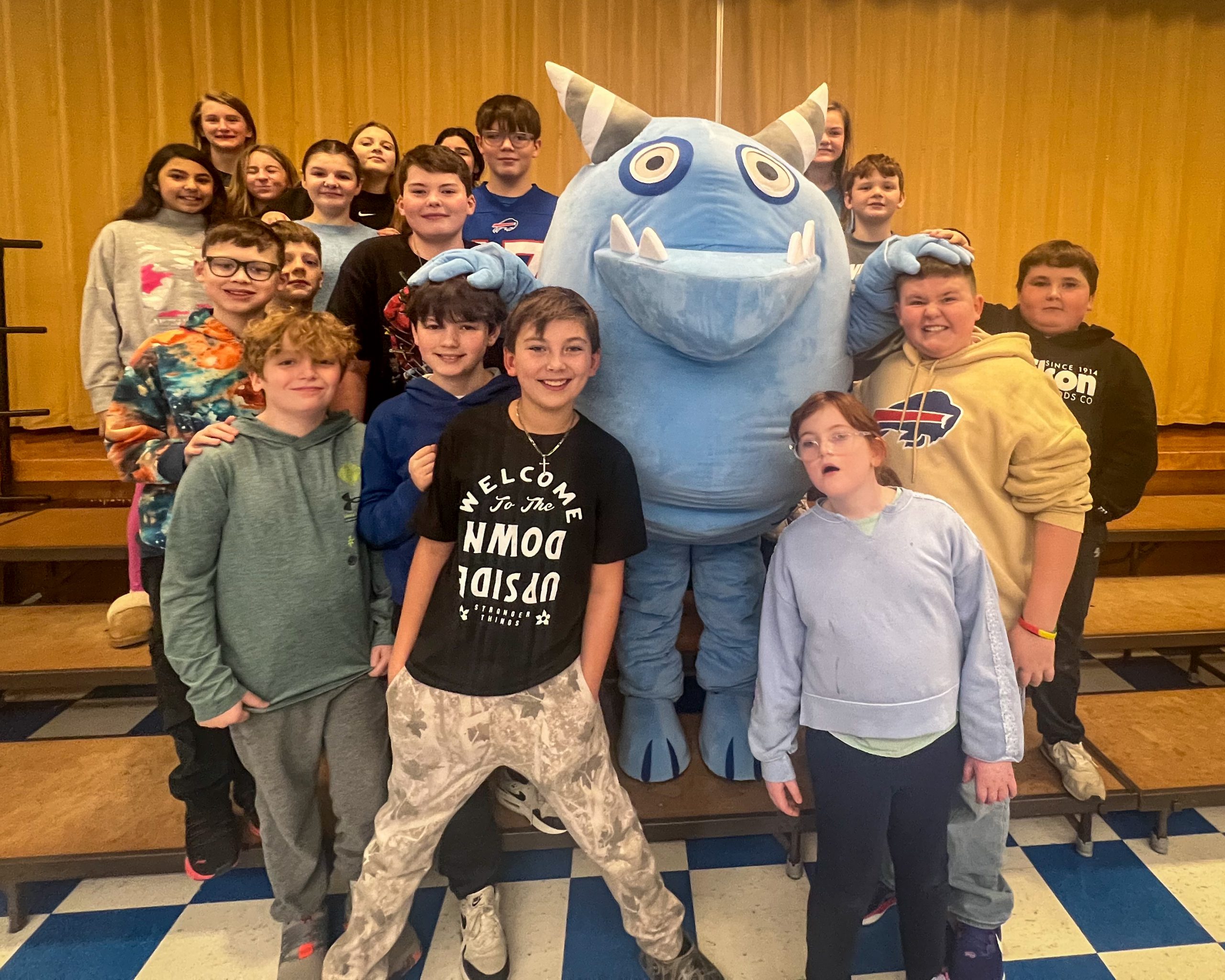 Small group of elementary students with a blue monster mascot