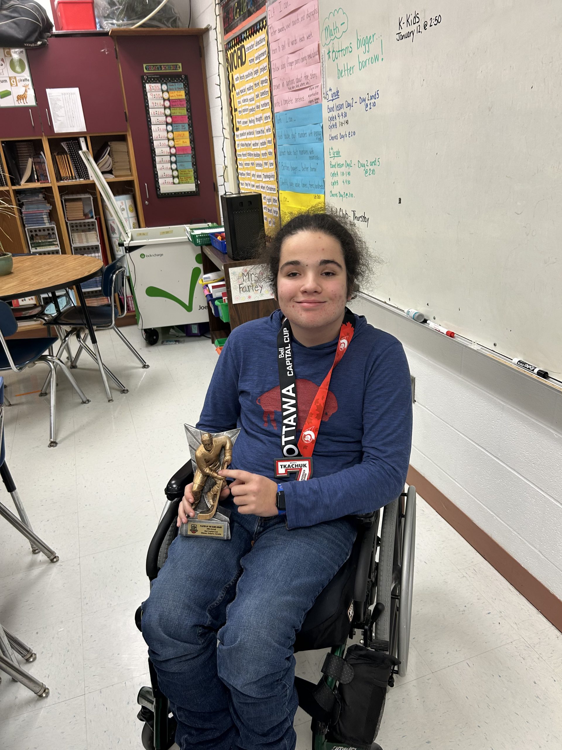Young male student in a wheelchair displaying his awards