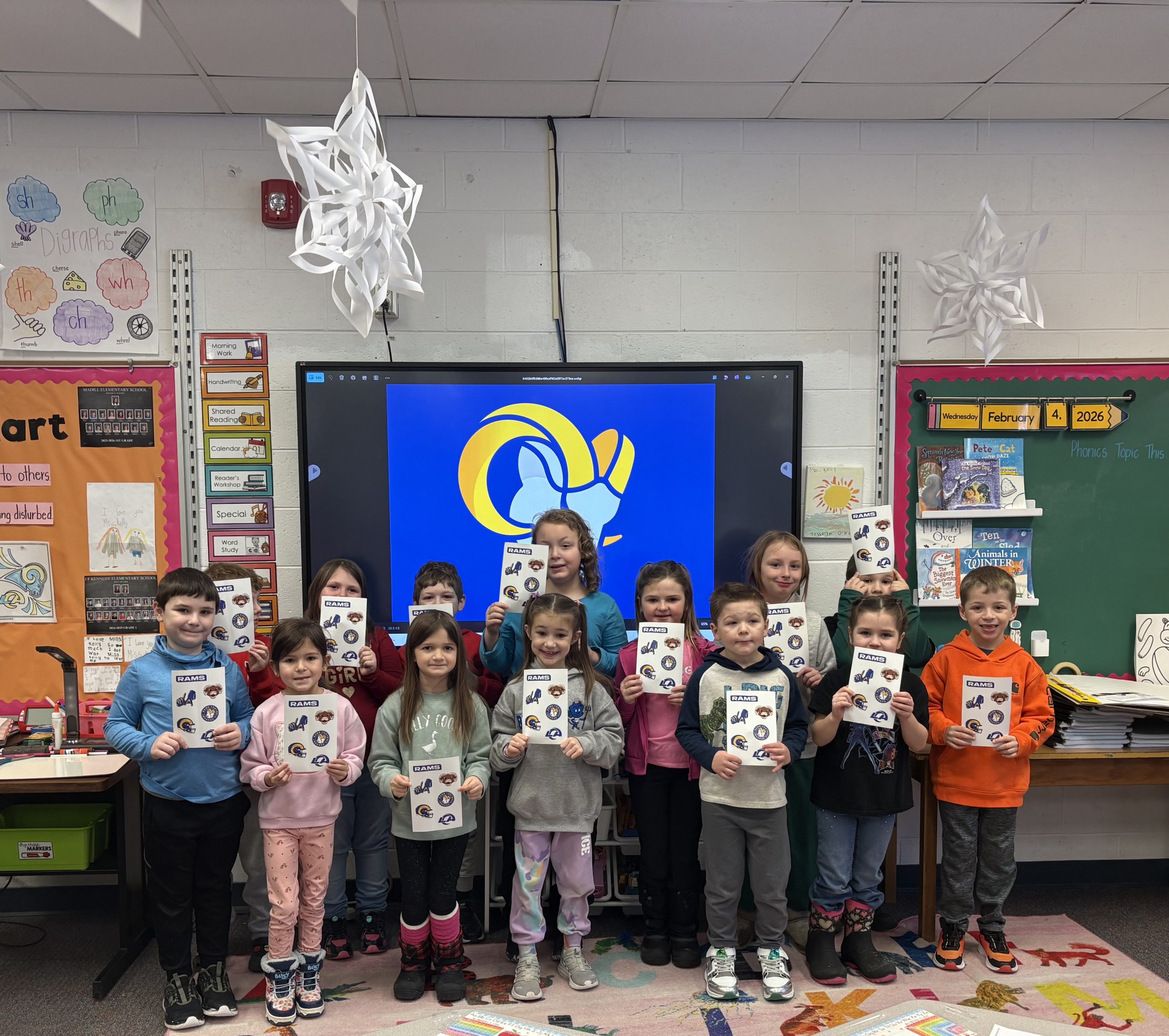 Small group of elementary students smiling with stickers in hand
