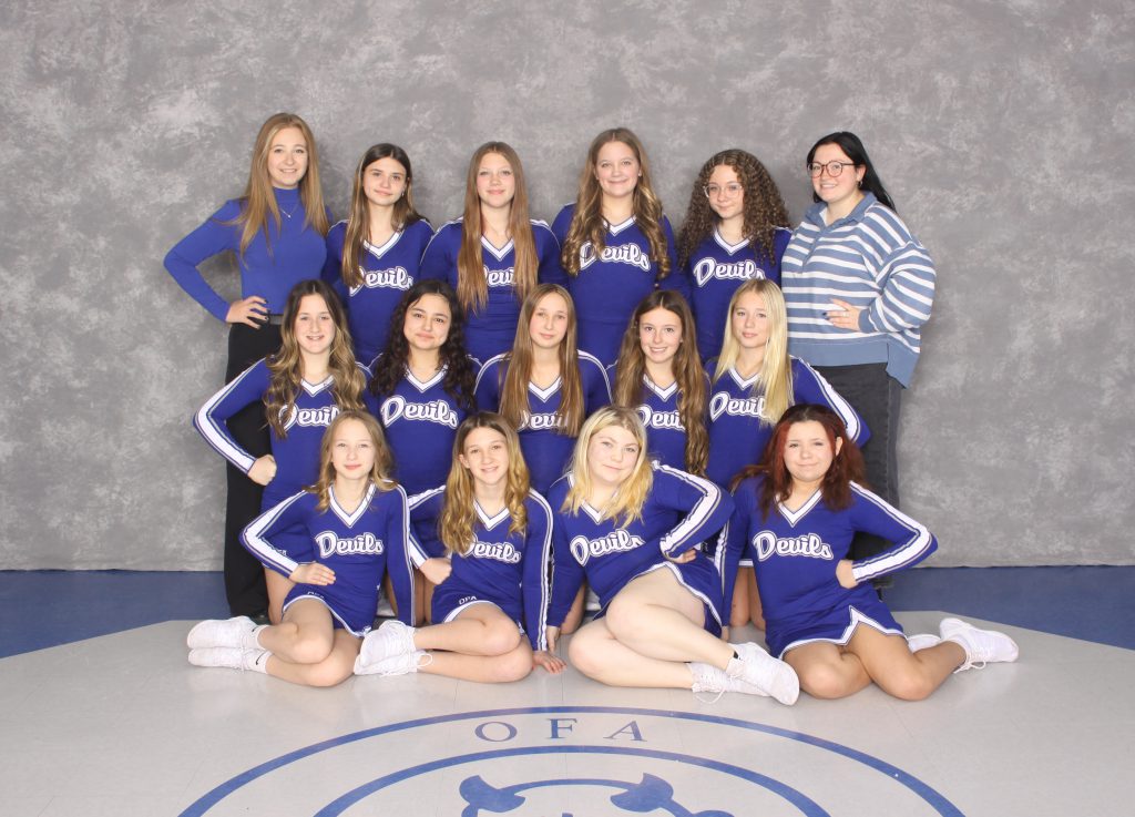 Small group of young female cheerleaders with female coaches