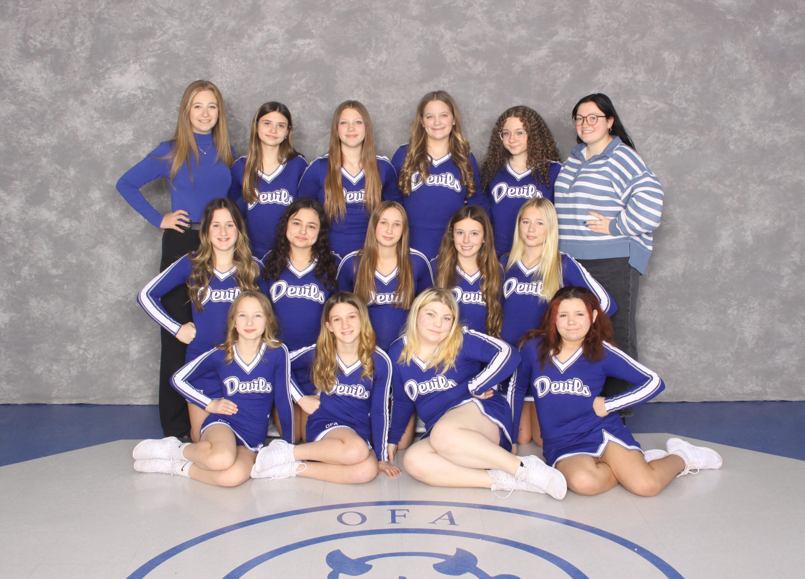 Small group of young female cheerleaders with female coaches