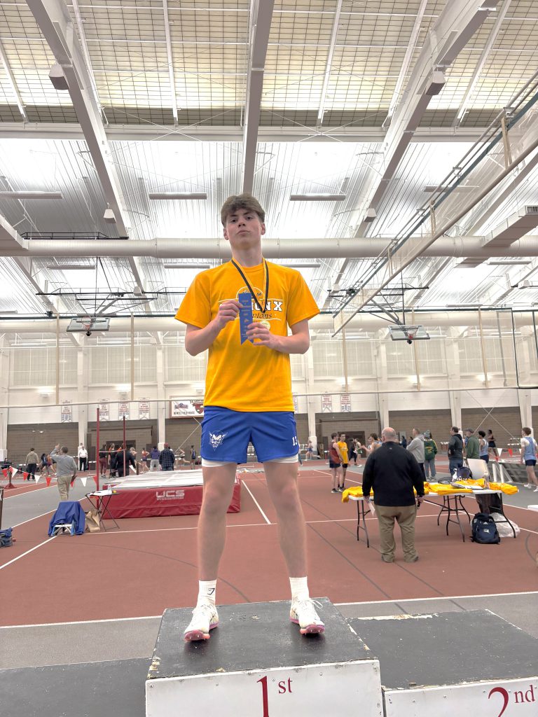 High school male indoor track and field athlete holding a ribbon