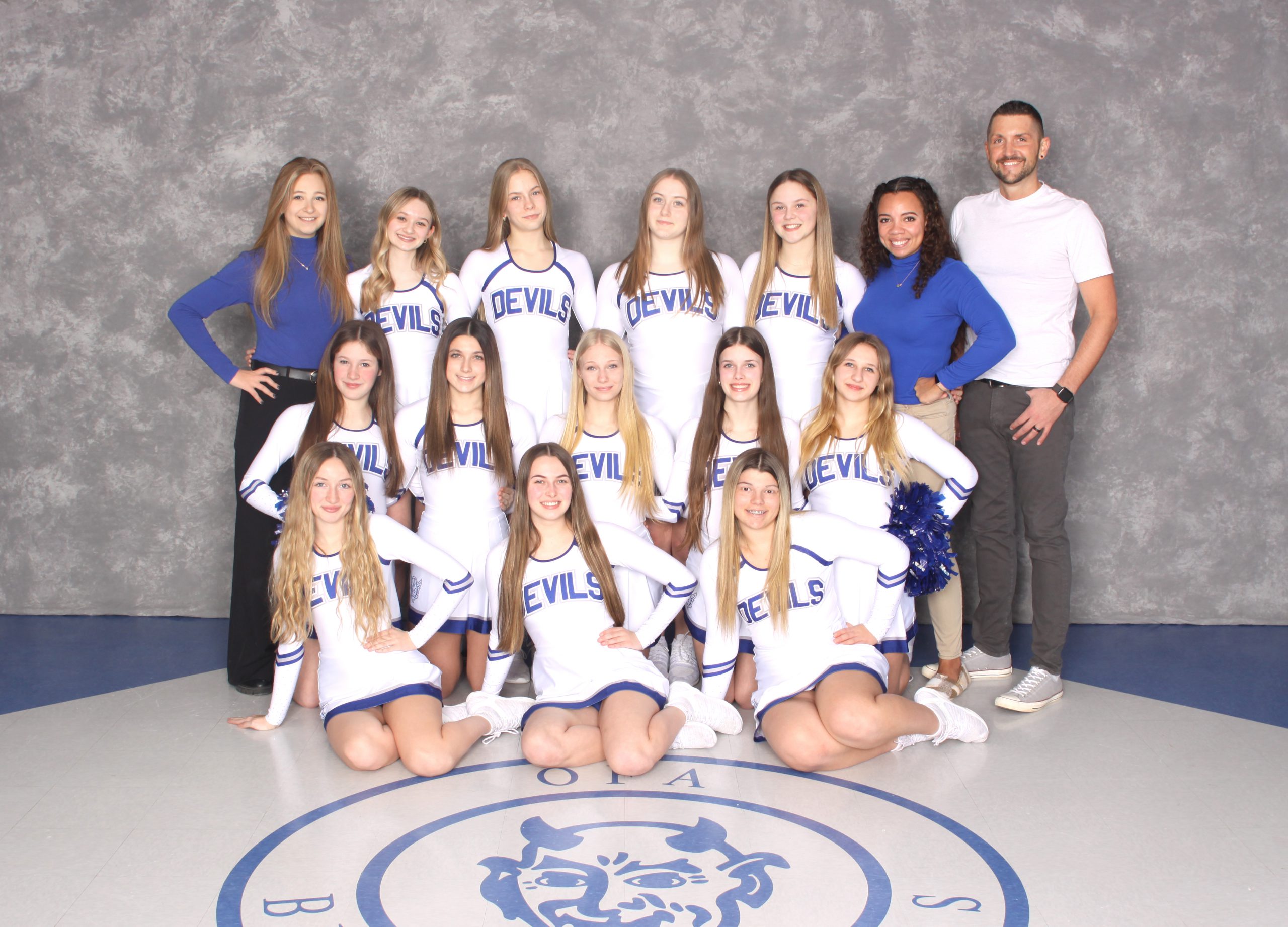 Small group of female high school cheerleaders with female and male coaches