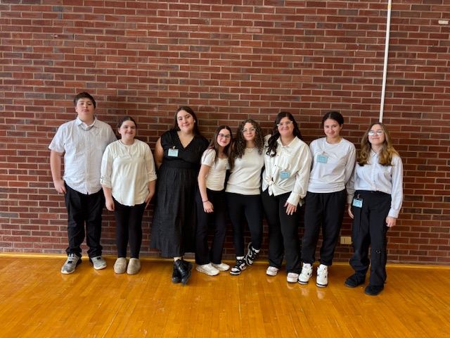 Small group of middle school students wearing white and black and smiling