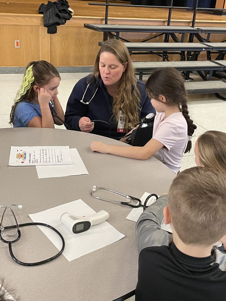 Adult female showing nursing tools to elementary students